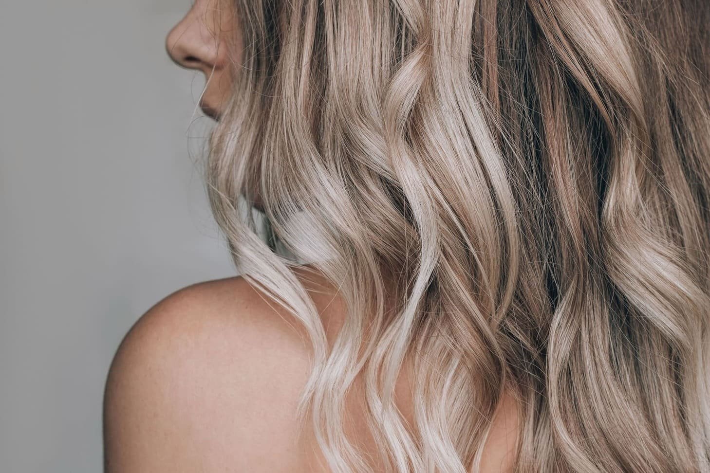 Młoda kobieta stojąca tyłem, zbliżenie na falowane włosy w kolorze blond